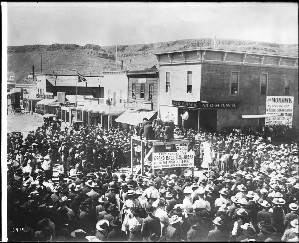 Crowd on a dirt street lined with wooden buildings in boomtown Goldfield, Nevada