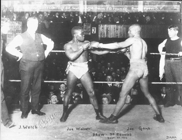 Boxers Joe Walcott and Joe Gans facing each other in the ring