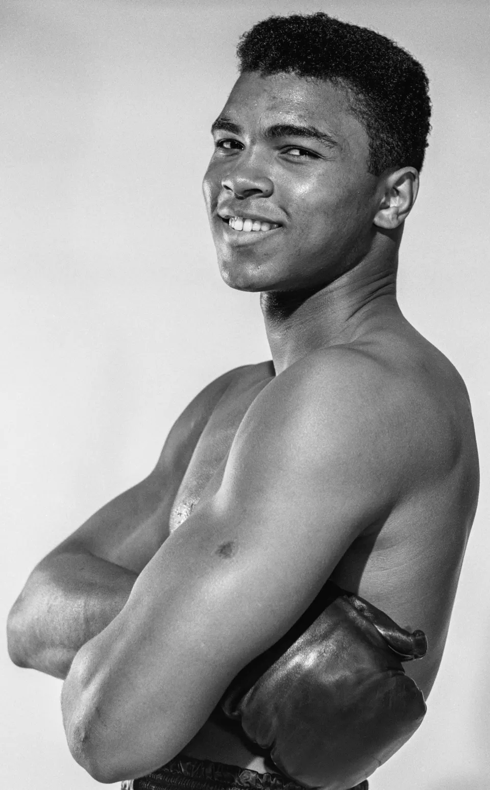 Black-and-white portrait of a smiling young Cassius Clay in 1962