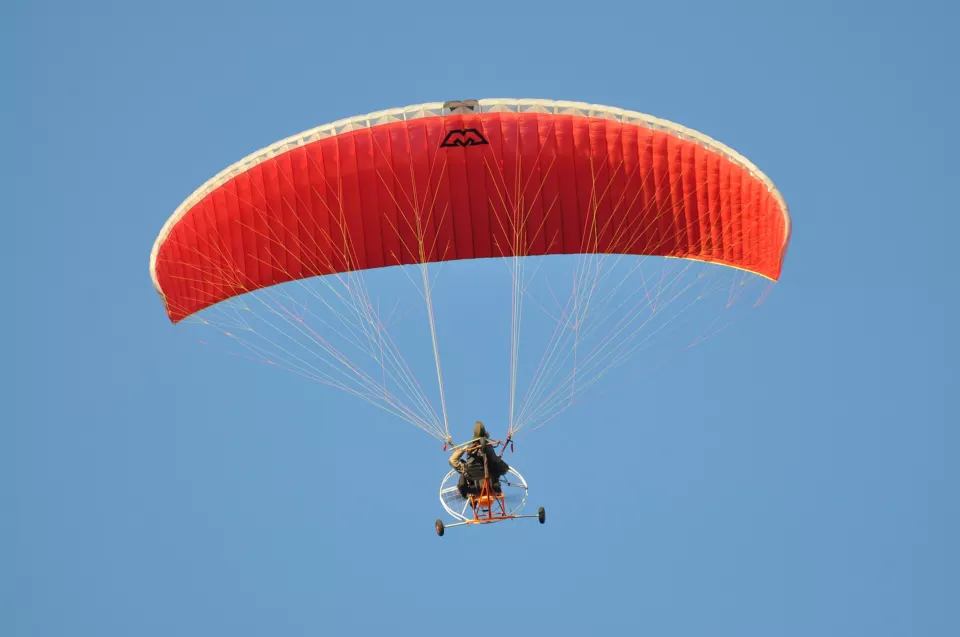 A pilot flying a powered paraglider with a backpack propeller