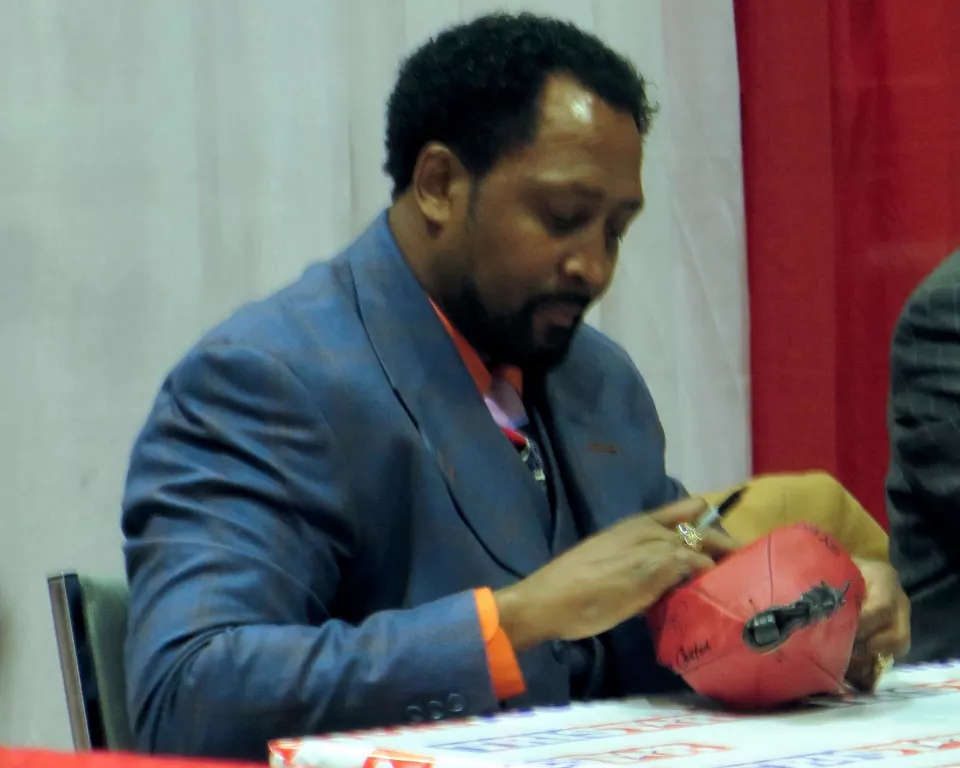 Thomas Hearns seated at a table signing autographs